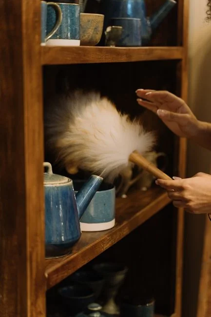 Person wearing full protective equipment disinfecting a leather sofa indoors, with careful attention to hygiene and safety.